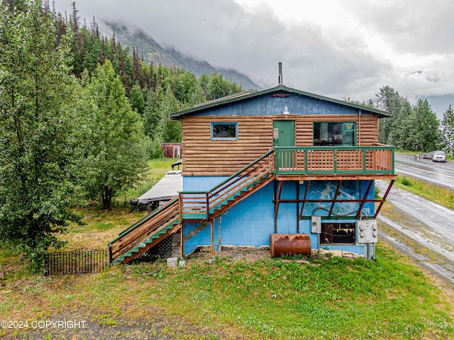 back of property featuring a mountain view and a lawn