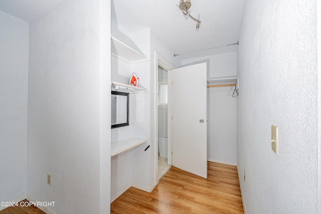 hall with rail lighting and light wood-type flooring