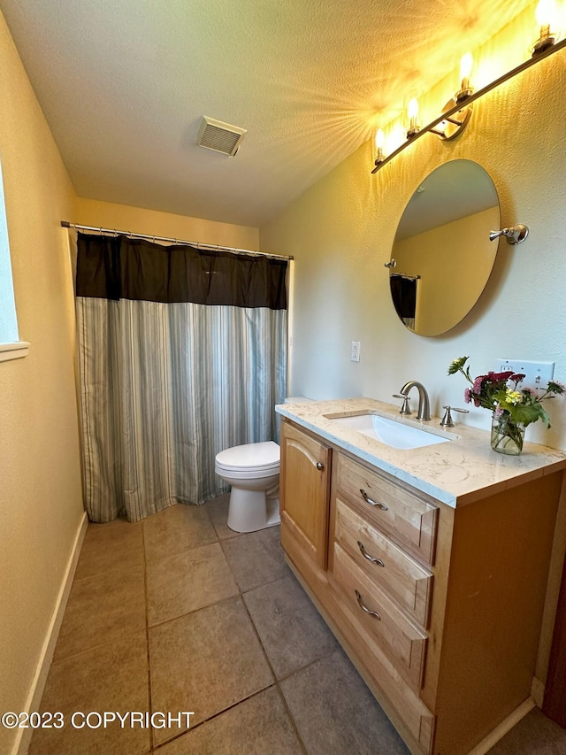 bathroom featuring vanity, toilet, a textured ceiling, and tile patterned flooring