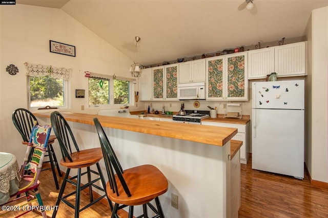 kitchen featuring white appliances, white cabinets, wood counters, dark hardwood / wood-style flooring, and a kitchen breakfast bar