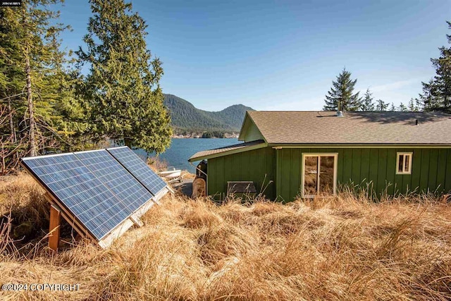 view of property exterior featuring a water and mountain view and solar panels