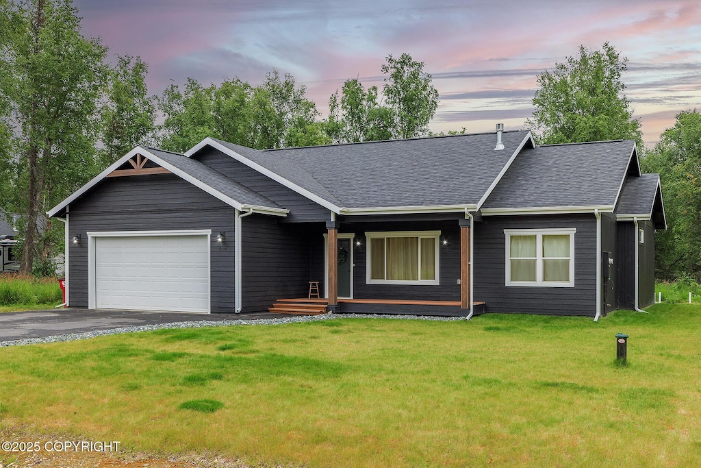 ranch-style home featuring a garage and a lawn