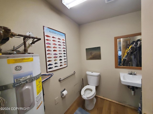 bathroom featuring electric water heater, hardwood / wood-style flooring, toilet, and sink