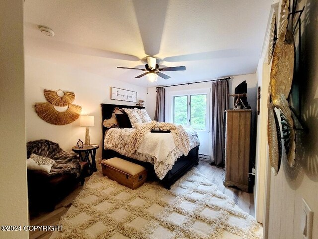 bedroom featuring a baseboard radiator, ceiling fan, and hardwood / wood-style flooring