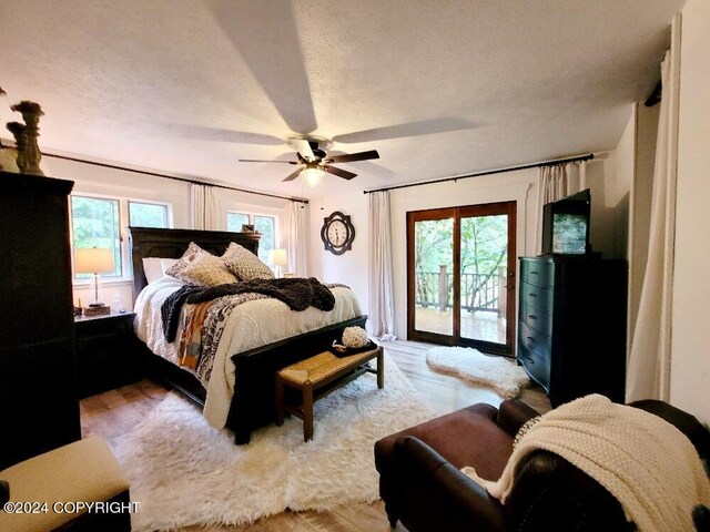 bedroom with multiple windows, access to outside, light wood-type flooring, and ceiling fan