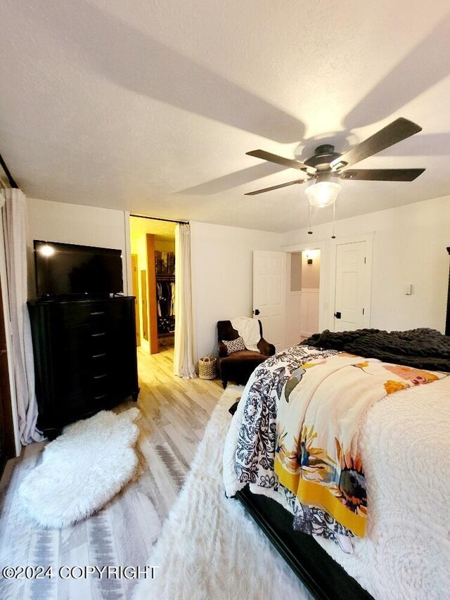 bedroom with a textured ceiling, ceiling fan, and light hardwood / wood-style flooring