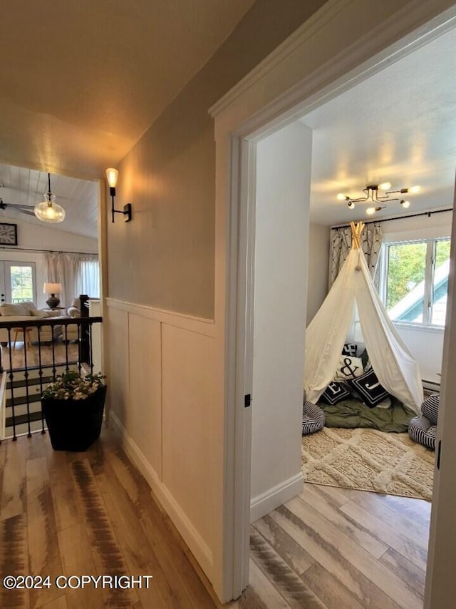 corridor featuring a healthy amount of sunlight, vaulted ceiling, and wood-type flooring