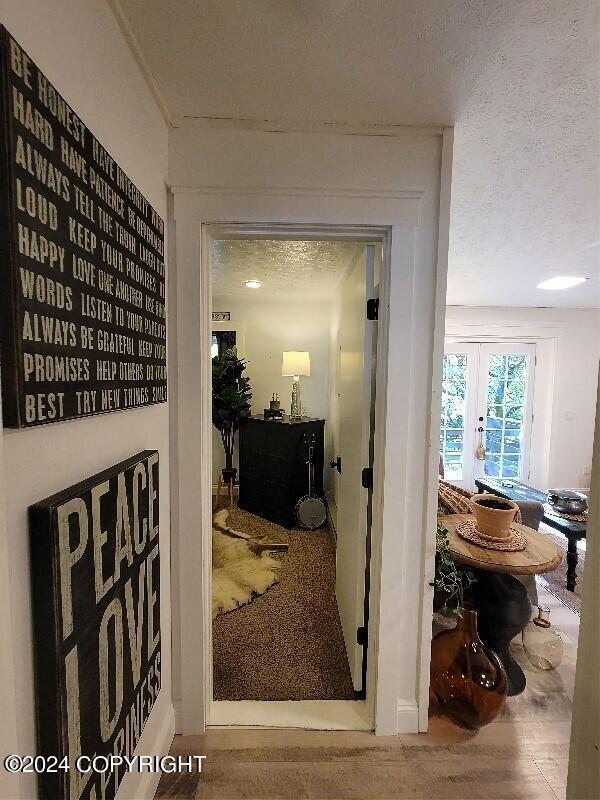 hall featuring a textured ceiling, wood-type flooring, and french doors