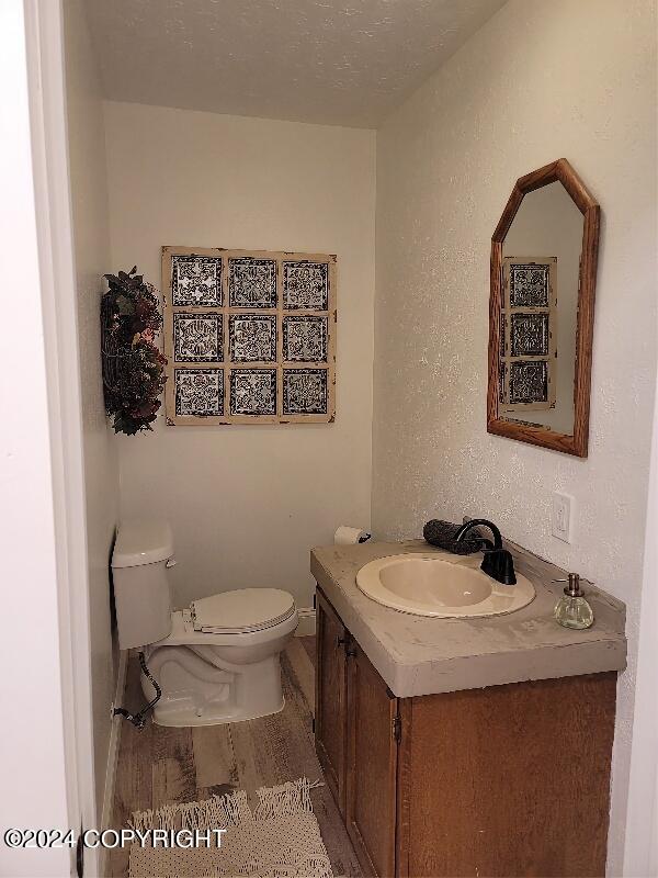 bathroom featuring hardwood / wood-style floors, a textured ceiling, vanity, and toilet