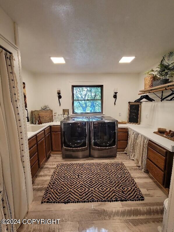 laundry room featuring cabinets, light wood-type flooring, and washing machine and clothes dryer