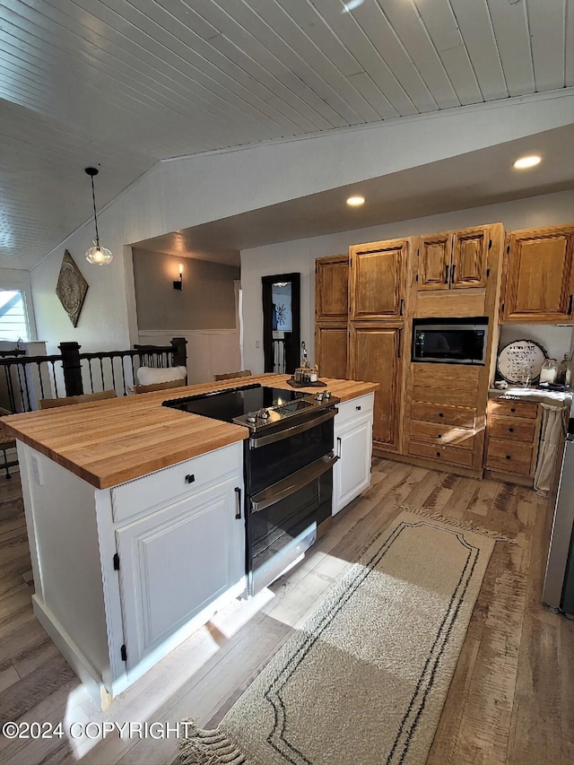 kitchen with wooden counters, light hardwood / wood-style flooring, white cabinetry, appliances with stainless steel finishes, and vaulted ceiling