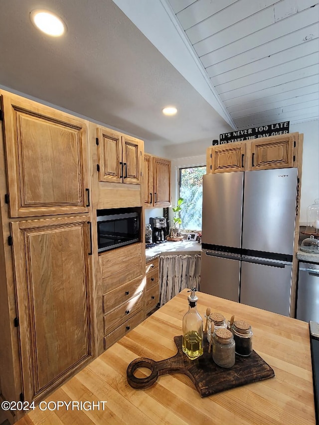 kitchen with stainless steel fridge, lofted ceiling, black microwave, and wood-type flooring