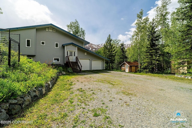 4477 Panther Dr, Eagle River, AK 99577 - view of side of property with gravel driveway and a garage
