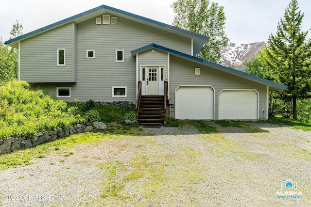 4477 Panther Dr, Eagle River, AK 99577 - view of front of home featuring a garage, gravel driveway, and a mountain view