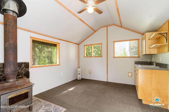 4477 Panther Dr, Eagle River, AK 99577 - unfurnished living room with a wood stove, a sink, ceiling fan, vaulted ceiling, and dark carpet