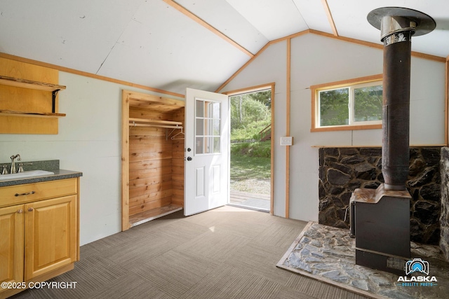 4477 Panther Dr, Eagle River, AK 99577 - kitchen with a wood stove, a sink, vaulted ceiling, dark countertops, and carpet floors