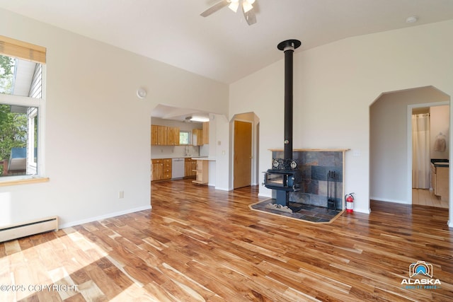 4477 Panther Dr, Eagle River, AK 99577 - unfurnished living room with a wood stove, arched walkways, light wood finished floors, a ceiling fan, and high vaulted ceiling