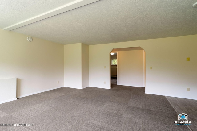 4477 Panther Dr, Eagle River, AK 99577 - unfurnished room with arched walkways, a textured ceiling, baseboards, and dark colored carpet