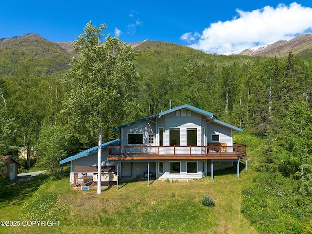 4477 Panther Dr, Eagle River, AK 99577 - rear view of house featuring a forest view, a deck with mountain view, an outdoor structure, and a lawn