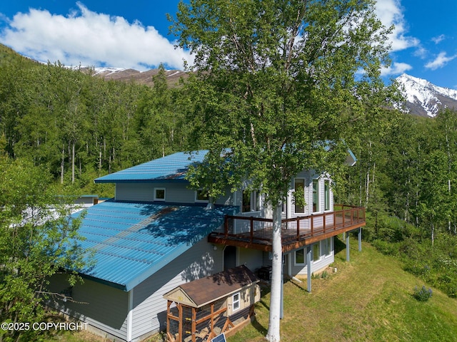 4477 Panther Dr, Eagle River, AK 99577 - rear view of house with a deck with mountain view, a lawn, and metal roof