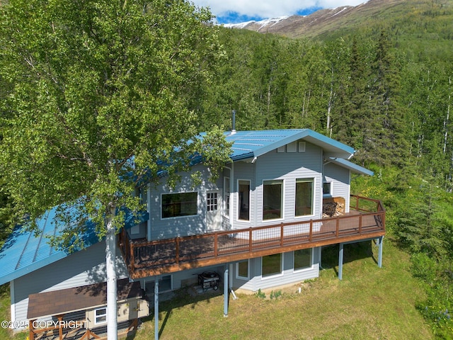 4477 Panther Dr, Eagle River, AK 99577 - rear view of house with a view of trees, a deck with mountain view, a lawn, and metal roof