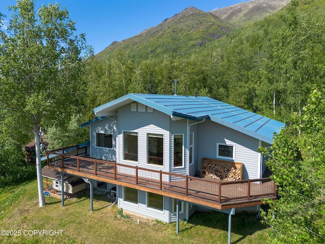 4477 Panther Dr, Eagle River, AK 99577 - rear view of house with a deck with mountain view, metal roof, a wooded view, and a lawn