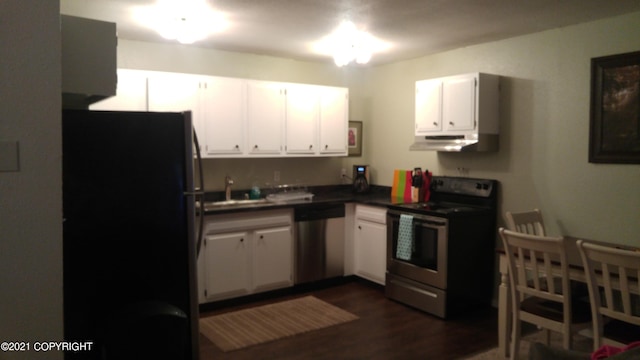 kitchen featuring dark wood finished floors, white cabinets, appliances with stainless steel finishes, under cabinet range hood, and dark countertops