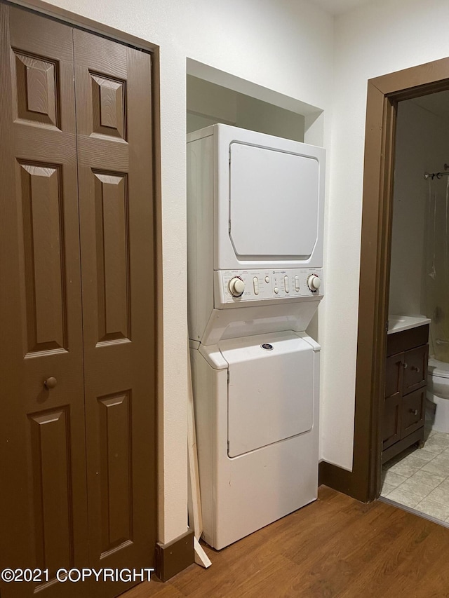 laundry area with laundry area, light wood-style floors, and stacked washing maching and dryer