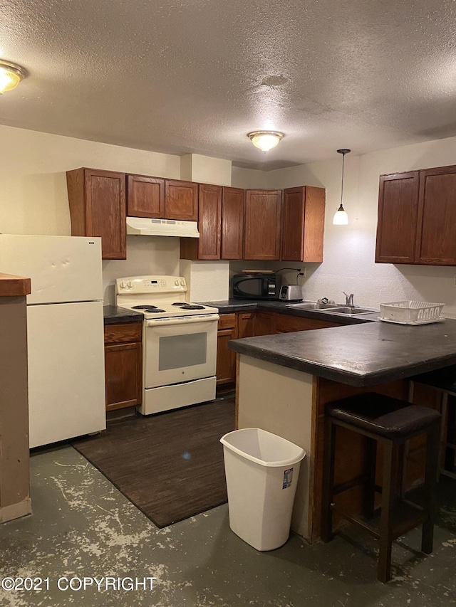 kitchen featuring white appliances, a peninsula, hanging light fixtures, under cabinet range hood, and dark countertops