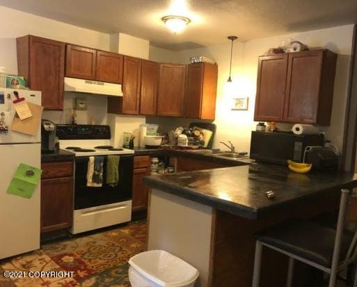 kitchen with under cabinet range hood, dark countertops, freestanding refrigerator, and electric range oven