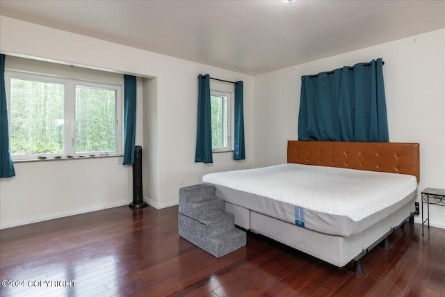 bedroom with dark wood-type flooring and multiple windows