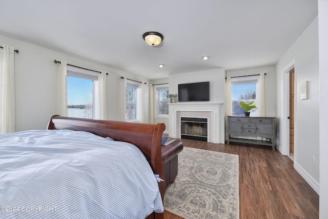 bedroom with a fireplace and dark wood-type flooring