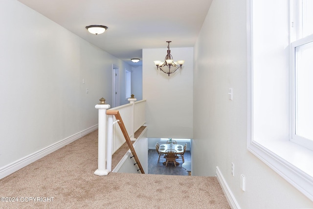 stairs featuring a notable chandelier and carpet floors