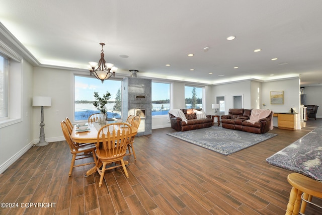 dining room featuring a notable chandelier, a fireplace, dark hardwood / wood-style floors, and a water view