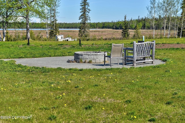 view of property's community featuring a water view, an outdoor fire pit, and a lawn