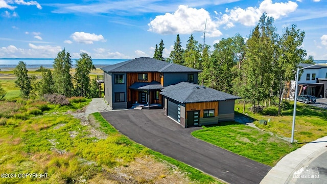 view of front of house with a garage, a water view, and a front lawn