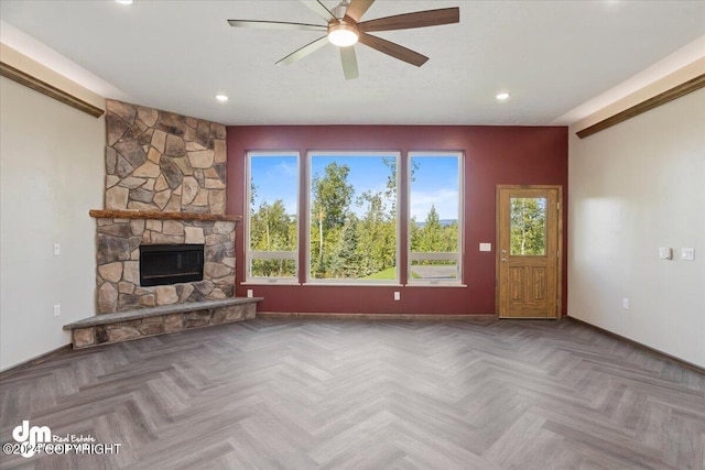 unfurnished living room featuring ceiling fan, a fireplace, and parquet floors