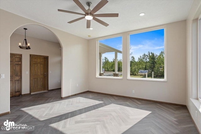 unfurnished room with ceiling fan with notable chandelier and parquet flooring