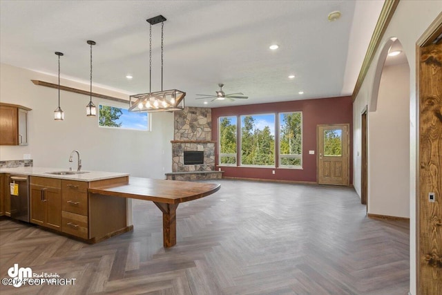 kitchen with hanging light fixtures, a fireplace, stainless steel dishwasher, dark parquet flooring, and sink