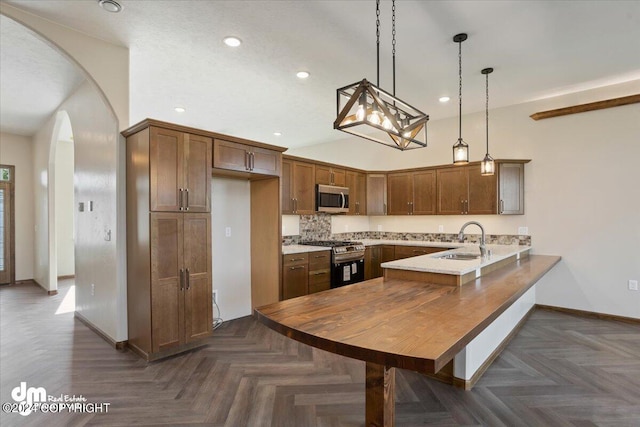 kitchen featuring dark parquet floors, range, sink, decorative backsplash, and kitchen peninsula