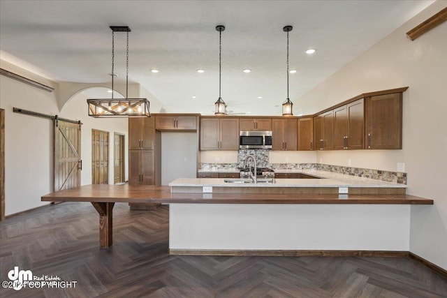 kitchen featuring appliances with stainless steel finishes, a barn door, dark parquet flooring, and sink