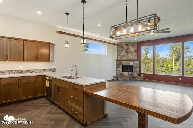 kitchen featuring kitchen peninsula, a fireplace, dark parquet flooring, decorative light fixtures, and sink