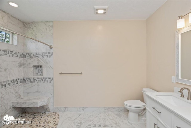 bathroom featuring a tile shower, vanity, and tile patterned flooring