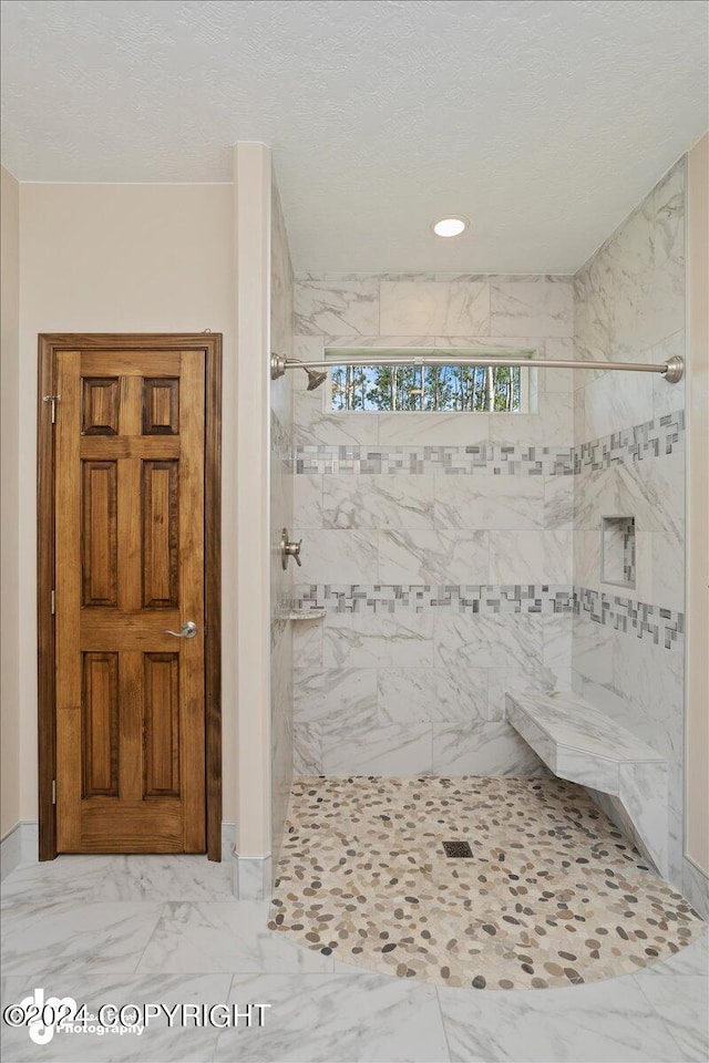 bathroom featuring a tile shower, a textured ceiling, and tile patterned flooring