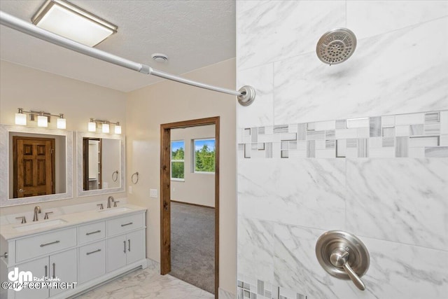 bathroom featuring double sink vanity, tiled shower, and tile patterned flooring