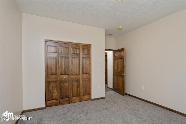 unfurnished bedroom with a textured ceiling and light carpet