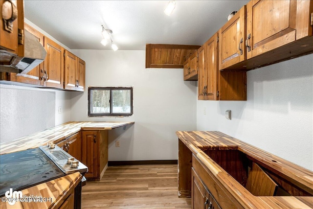 kitchen featuring wooden counters, rail lighting, light hardwood / wood-style flooring, and a textured ceiling