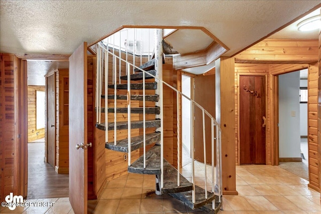 interior space featuring a textured ceiling and wood walls