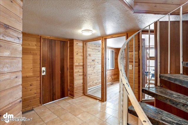 entrance foyer featuring a textured ceiling and wood walls