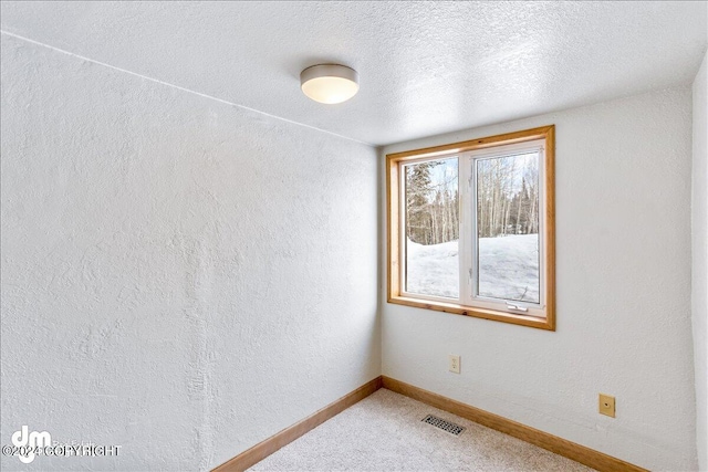 carpeted empty room featuring baseboards, visible vents, a textured ceiling, and a textured wall